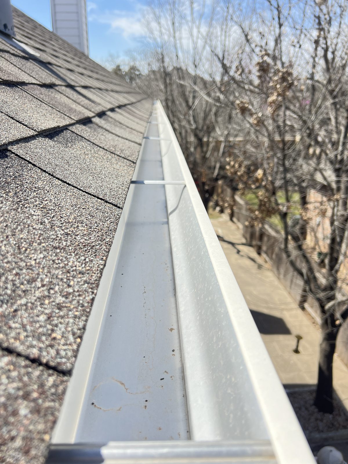Hand-cleaned residential gutter in Austin, debris cleared and downspout flushed